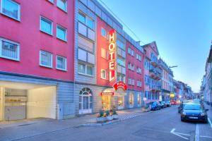 a building with a neon sign on the side of a street at Ambassador TheContinents in Karlsruhe