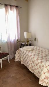 una camera con un letto e una sedia e una finestra di Villa i tre Cipressi ad Agnano
