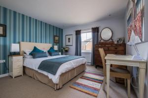 1 dormitorio con cama, escritorio y espejo en Camber Cottage, en Camber