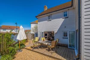 a patio with a table and chairs and a house at Camber Cottage in Camber
