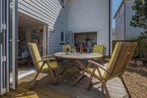 a patio with a table and chairs on a deck at Camber Cottage in Camber