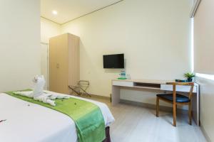 um quarto com uma cama, uma secretária e uma televisão em Best Inn Balikpapan em Balikpapan