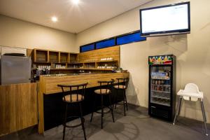 a bar with stools and a tv on the wall at Best Inn Balikpapan in Balikpapan