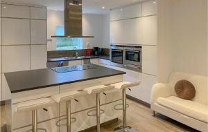 eine Küche mit weißen Schränken, einer Theke und einem Stuhl in der Unterkunft Beautiful Home In Mjlby With Ethernet Internet in Mjölby