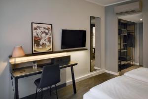 1 dormitorio con escritorio, TV y cama en THE SCOTTY Hotel Hamburg, en Hamburgo