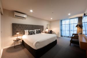 Cette chambre comprend un grand lit et un bureau. dans l'établissement Avenue Hotel Canberra, à Canberra