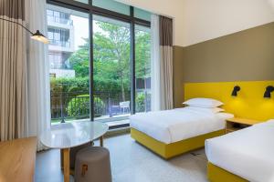 una camera d'albergo con due letti, un tavolo e una finestra di SongShan Lake PingShang Serviced Hotel a Huangcaolang