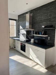a kitchen with white cabinets and a black wall at Joli T4 en centre historique in Montauban +16 photos