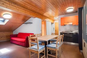 cocina con mesa y sillas y sofá rojo en Residence Viola en Andalo