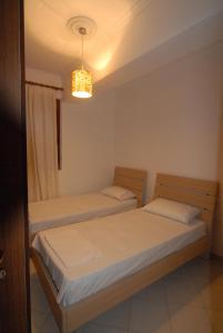 two twin beds in a room with a chandelier at Orikum Veranda Apartments in Orikum