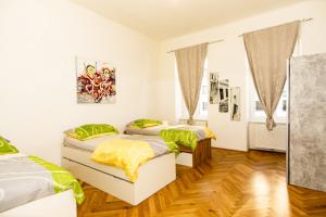 two beds in a room with white walls and wooden floors at Raimond Apartment in Vienna