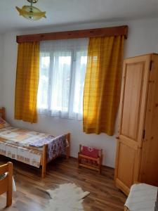 ジルダ・デ・ススにあるCasa de Vacanta Joldesのベッドルーム1室(ベッド1台付)、黄色いカーテン付きの窓が備わります。