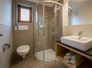 La salle de bains est pourvue d'une douche, d'un lavabo et de toilettes. dans l'établissement Garnì Lasteis B&B - apartments, à La Villa