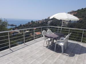 eine Terrasse mit einem Tisch, Stühlen und einem Sonnenschirm in der Unterkunft Nino Lux Apartments Ulcinj in Ulcinj