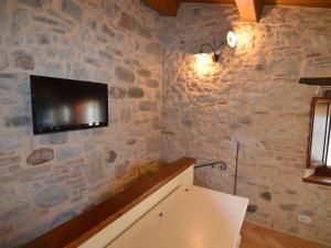 Cette chambre dispose d'une télévision sur un mur en pierre. dans l'établissement Appealing Apartment in Petrella Guidi with near Centre, à Petrella Guidi