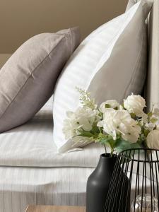 eine weiße Couch mit Kissen und eine Vase Blumen in der Unterkunft Хотел BLISS in Kazichene