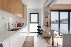 a kitchen with white cabinets and a counter with chairs at GuestReady - A modern retreat in Porto in Porto