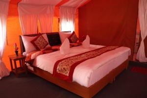 a bedroom with a large bed with red walls at Ldazes Camp in Hundar