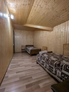 two beds in a room with wooden walls and wooden floors at Doxturi's sakhli in Shatili