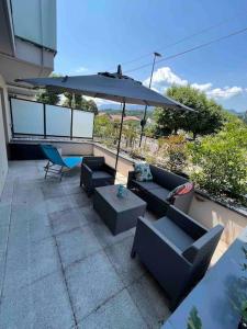a patio with couches and an umbrella and a table at Spacieux Appart T3+terrasse in Aix-les-Bains