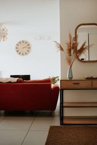 a living room with a red couch and a clock on the wall at Spacieux Appart T3+terrasse in Aix-les-Bains