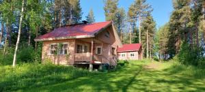 ein Haus mit rotem Dach in der Mitte eines Feldes in der Unterkunft Pulla Karvisen Maatilamatkailussa in Ruokola