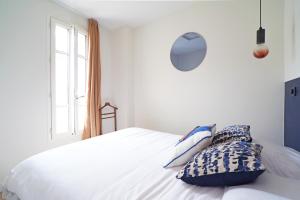 Un dormitorio con una cama blanca con almohadas. en Villa Adèle, Bow-Window vue Mer -Appt 04 en Mers-les-Bains