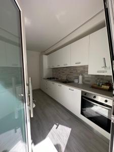 a kitchen with white cabinets and a glass door at A do Passi dal Mare in Chioggia
