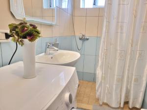 La salle de bains blanche est pourvue d'un lavabo et d'un vase fleuri. dans l'établissement KORETA APARTMENT, à Vlorë