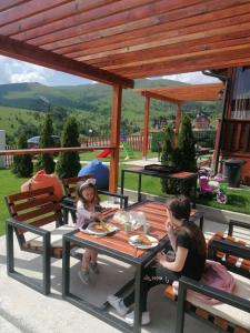 a man and a little girl sitting at a table at Zlatibor Brvnara Mir in Zlatibor