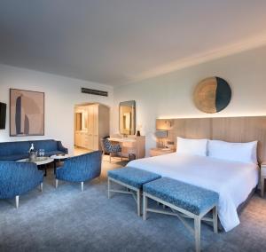 ein Hotelzimmer mit einem großen Bett und Stühlen in der Unterkunft Victoria & Alfred Hotel by NEWMARK in Kapstadt