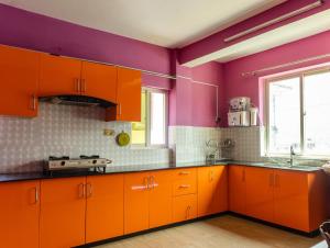 a kitchen with orange cabinets and purple walls at Season homestay in Kathmandu