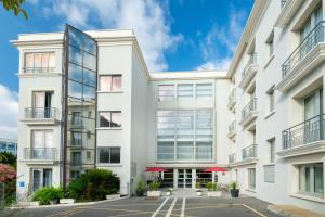 an exterior view of a white building with red umbrellas at Best Western Hôtel Journel Antibes Juan-les-Pins in Antibes