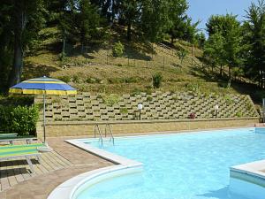 ApecchioにあるCountry Cottage in Marche with Swimming Poolの大型スイミングプール(パラソル、椅子付)
