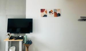 a flat screen tv on a white wall with two pictures at 味知旅宿 Unknown house in Xiaoliuqiu