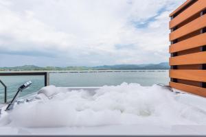 a bath tub covered in snow next to a body of water at ลีฟ เลค กาญจน์ รีสอร์ท in Ban Hin Hak