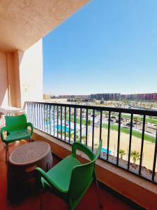 a balcony with two green chairs and a view of a pool at Prime chalet in Golf Porto Marina resort new Alamein in El Alamein