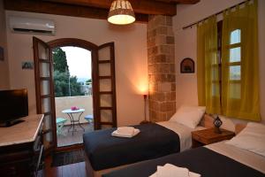 a bedroom with two beds and a television and a balcony at VILLA VICTORIA OLD TOWN in Rhodes Town