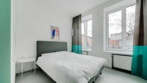 a white bedroom with a bed and two windows at New York Laisvės al 51A in Kaunas