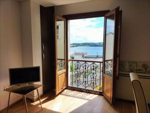 a room with a door open to a balcony with a television at Bonito y acogedor apartamento en Castropol in Castropol