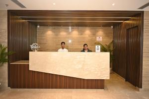 two people standing at a counter in a lobby at Sachika Hotels, Guwahati in Guwahati