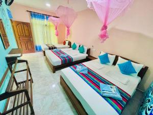 two beds in a room with pink and blue decorations at Gangadiya Lodge in Sigiriya