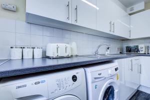 eine Küche mit einer Waschmaschine und einem Waschbecken in der Unterkunft Inviting Urban Apartment in Croydon in Croydon