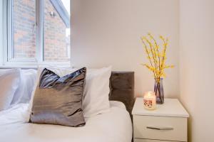 ein Kissen auf einem Bett neben einem Nachttisch in der Unterkunft Inviting Urban Apartment in Croydon in Croydon