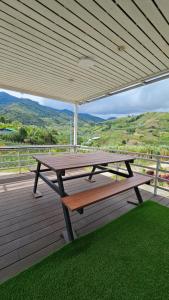 a picnic table and bench on a deck with a view at 15°C Lodge Kundasang in Kampong Kundassan