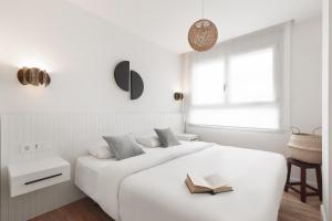 a white bedroom with a bed with a book on it at Port Forum Apartments by Olala Homes in Barcelona