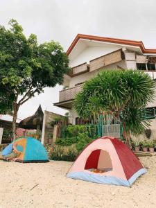 two tents on the sand in front of a house at Ella's Beach House in Tuble