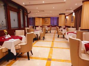 Royal Qatar Hotel في الدوحة: مطعم فيه طاولات وكراسي في الغرفة
