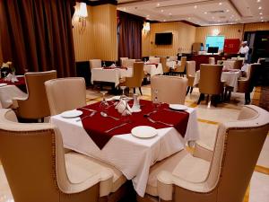 een eetkamer met witte tafels en stoelen en een tafel bij Royal Qatar Hotel in Doha