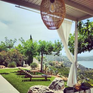 a patio with a table and chairs and a hanging light at Avatonblue Villa Nafplio in Vivari